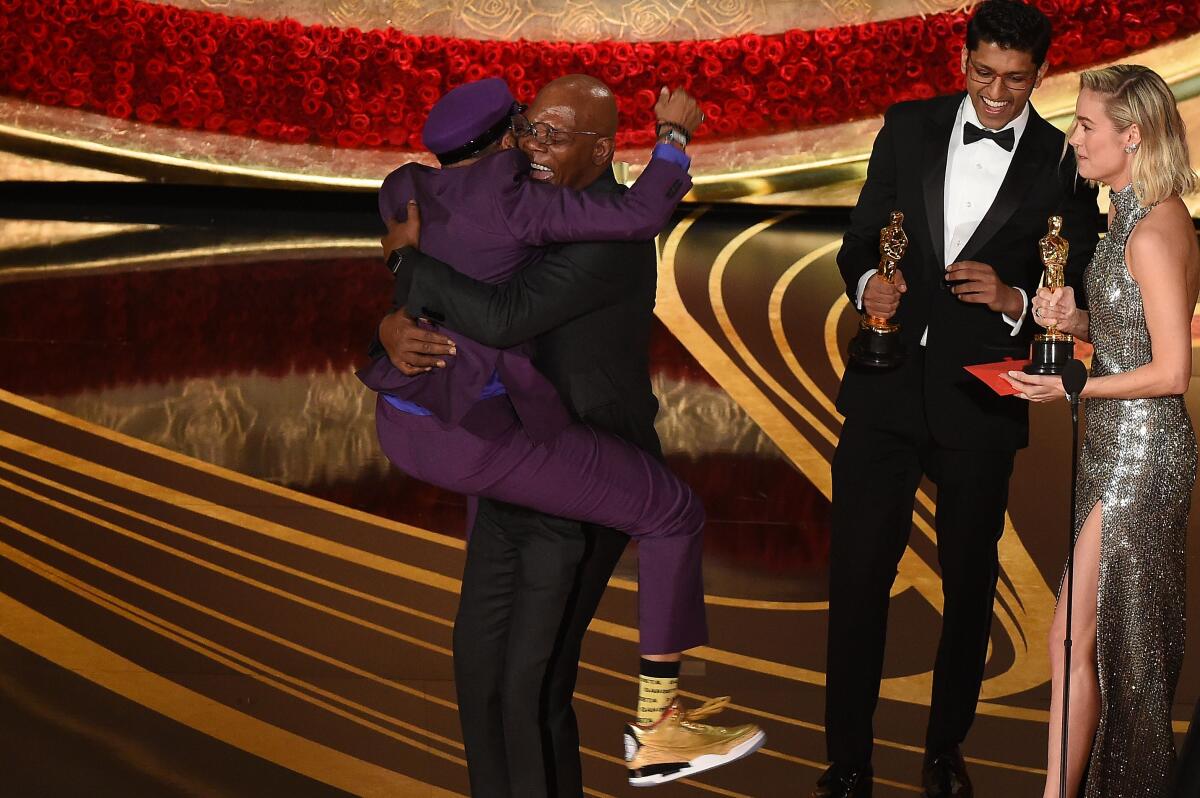 Spike Lee in a purple suit and golden Air Jordans jumps into the arms of Samuel L. Jackson on the Oscars stage