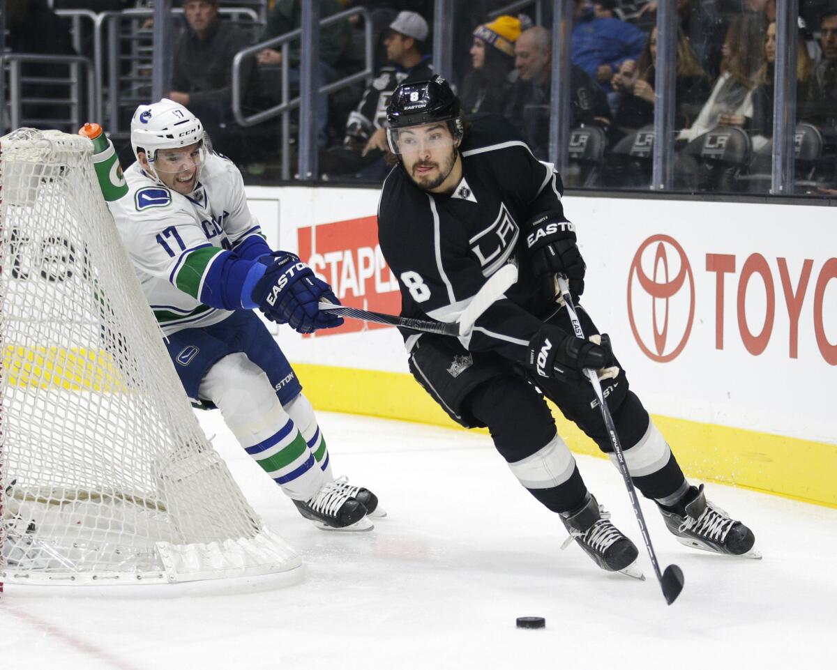 Kings defenseman Drew Doughty controls the puck while the Vancouver Canucks' Radim Vrbata slashes at his wrists during a Dec. 1 game at Staples Center.