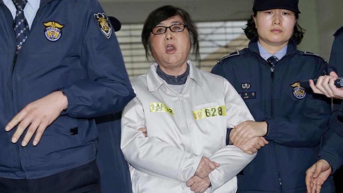 Choi Soon-sil, center, the jailed confidant of impeached South Korean President Park Geun-hye, shouts upon her arrival at the office of the independent counsel in Seoul on Jan. 25, 2017.