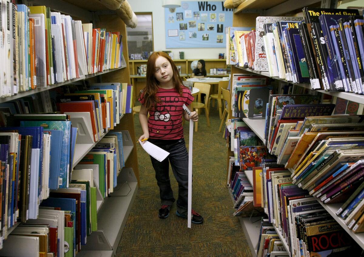 Katrina Polikolsky, 8, of La Crescenta, looks for clues during the How Tall Is It? scavenger hunt at the Montrose Library in Montrose on Wednesday, January 15, 2014. Participating children had to find 13 locations within the library and measure items mentioned in the clues. Once they finished the hunt, they received a small prize.