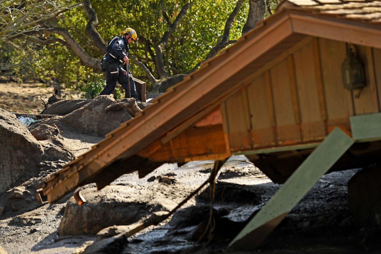 A member of the search and rescue team inpsects property near a home along Glen Oaks Drive in Montecito.