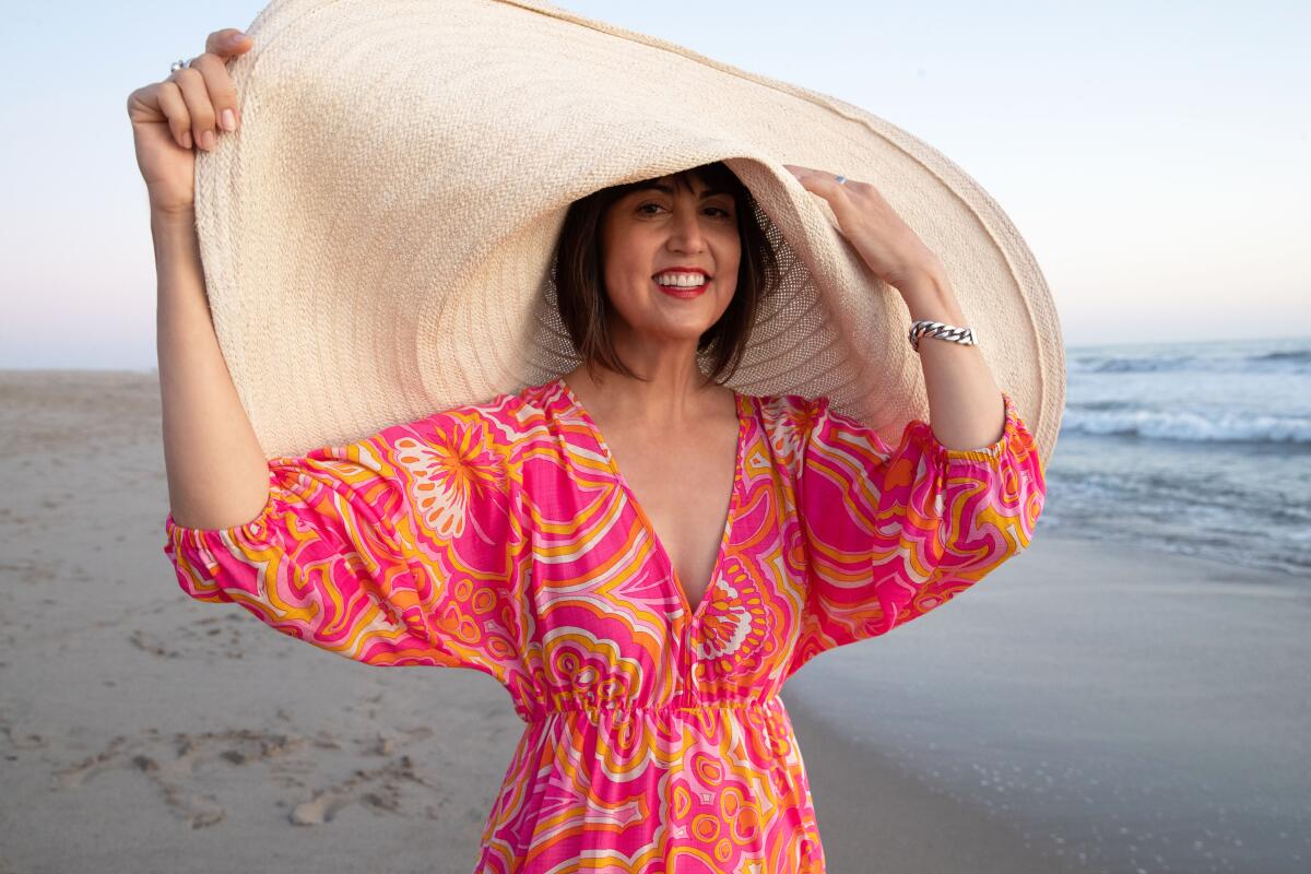 Designer Trina Turk wears a colorful printed dress and a huge straw hat.