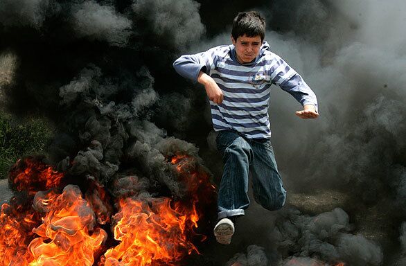 A Palestinian demonstrator jumps over burning tires during a protest over water supplies in the West Bank village of Nabi Salah. The water supply is used by Jewish settlers from the nearby settlement of Halamish and is claimed by both sides.