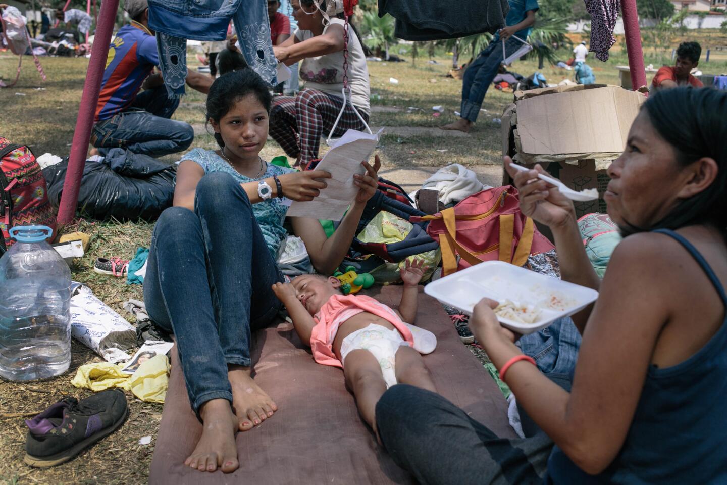 Ariyuri Garcia, 18, left, sits with her niece Ester Garcia Rivera, 21 months old, while they camp out with other members of an immigrant caravan at a sports stadium in Matias Romero, Mexico. The baby has been sick with chest congestion during the journey. The family plans to go to Tijuana if they can’t get to the U.S.