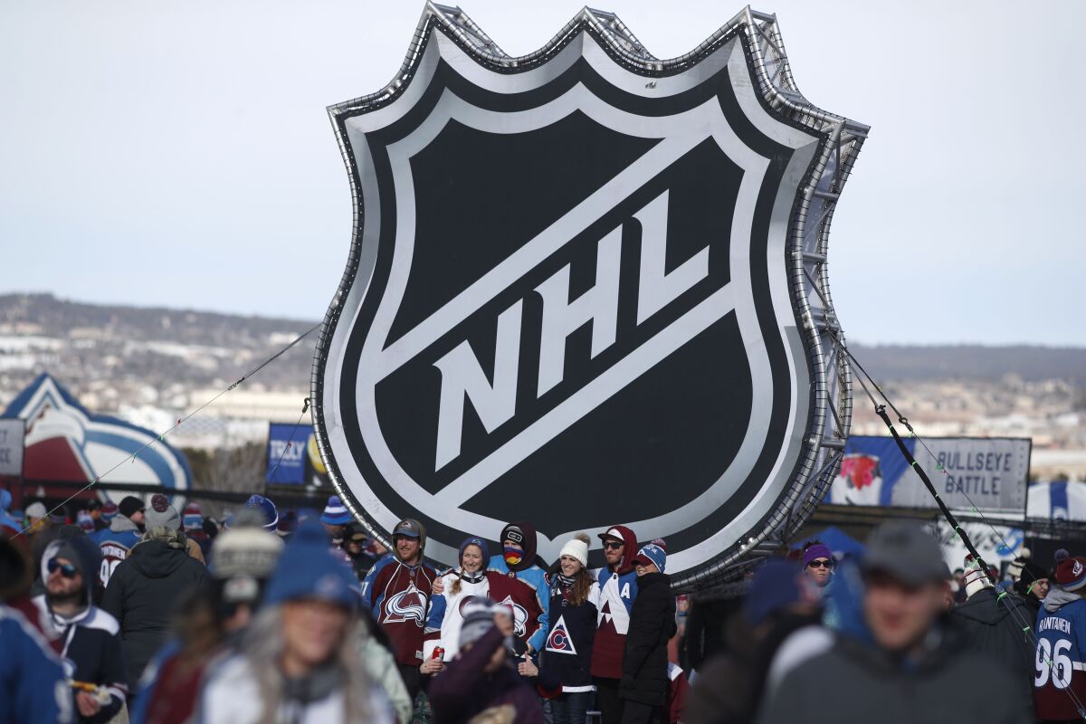Fans pose below the NHL league logo