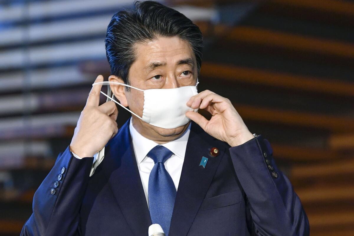 Japanese Prime Minister Shinzo Abe takes off his mask as he speaks to reporters at the prime minister's official residence in Tokyo on Monday. 