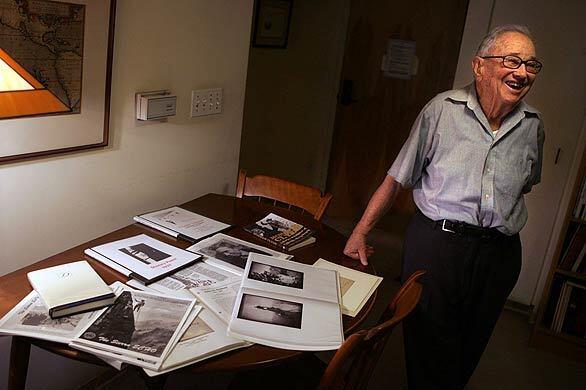 Glen Dawson, 96, the patriarch of Sierra mountaineering, stands next to a table in his Pasadena apartment that holds books and records of his exploits. He was in the first party to scale the east face of Mt. Whitney in 1931. He climbed with Brower and served with him in World War II.