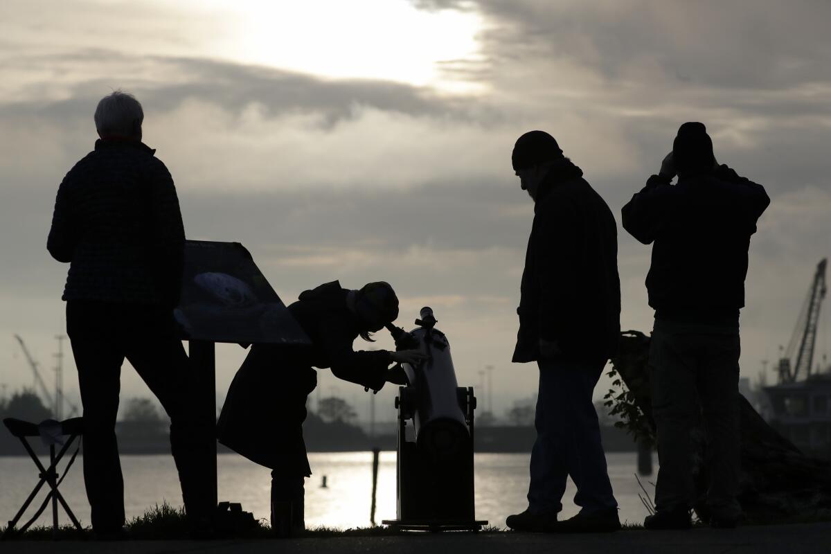 Skywatchers in Seattle look on during a brief break in the clouds to see a transit of the planet Mercury as it crosses the face of the sun on Monday. Mercury and Venus are the only planets that can appear to pass in front of, or transit, the sun as seen from Earth.