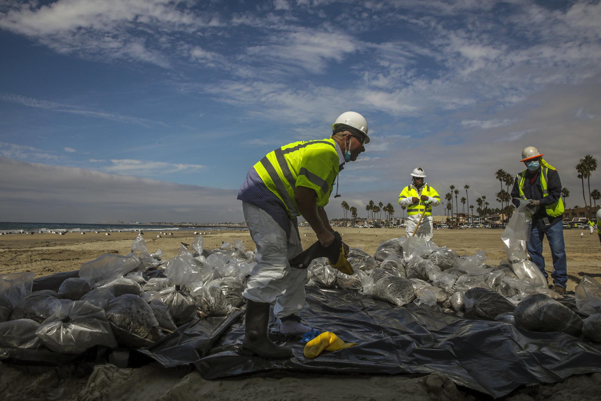 Workers in hard hats on a beach. 
