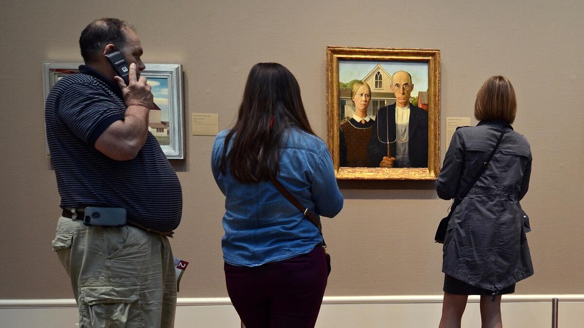 The original "American Gothic" isn't in Iowa, where Grant Wood was born. It's in Chicago at the Chicago Art Institute, where visitors stop to contemplate.