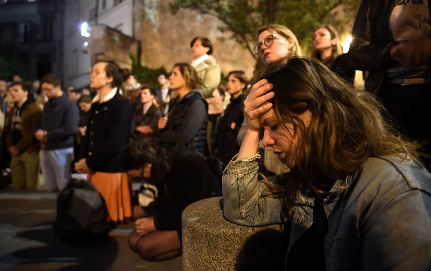 People kneel as they pray outside and watch the Notre Dame fire. A ferocious and fast-moving blaze, which broke out about 6:45 p.m., destroyed large parts of the 850-year-old Gothic monument in Paris.