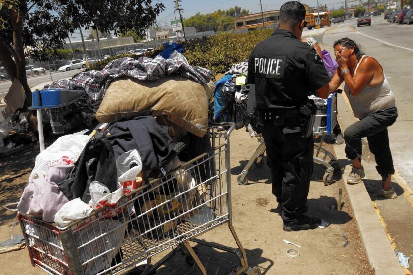Los Angeles Police Officer Hector Ramirez tells Rosa Torres that she will have to gather what she can before a sweep of her encampment on a median on Parthenia Place in North Hills in July.