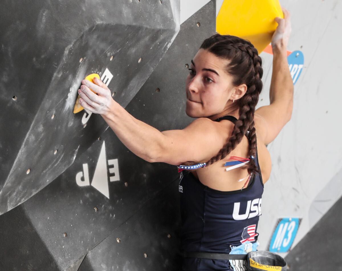 Brooke Raboutou holds on while climbing a vertical wall.