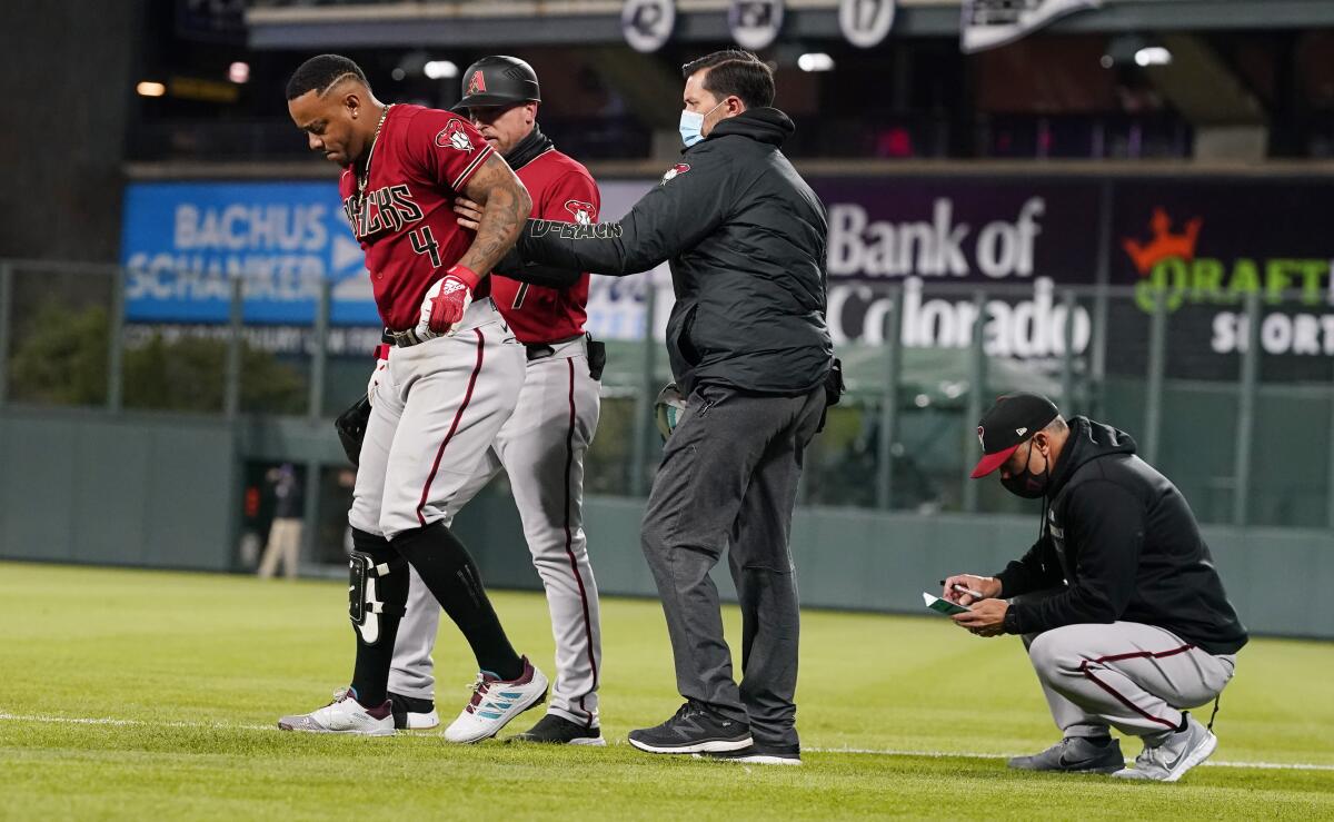 Arizona Diamondbacks' Ketel Marte, left, is helped off the field after injuring his leg while running out a ground ball during the sixth inning of the team's baseball game against the Colorado Rockies on Wednesday, April 7, 2021, in Denver. (AP Photo/David Zalubowski)