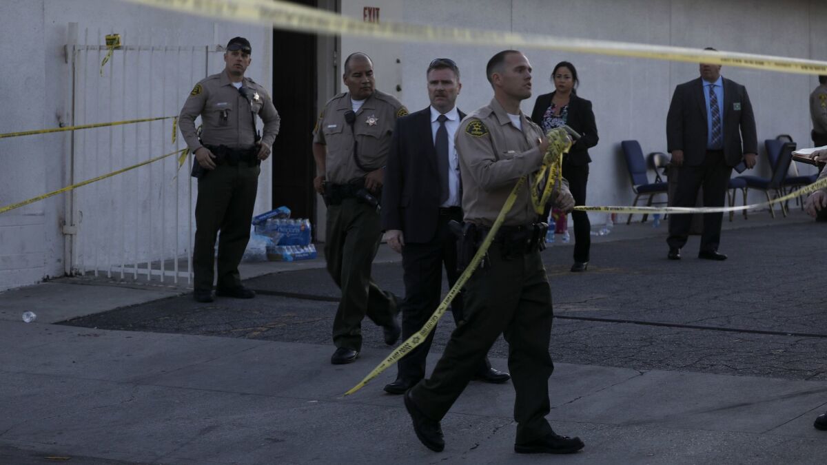A Los Angeles County sheriff's deputy removes tape from the parking lot entrance outside the church in Compton.