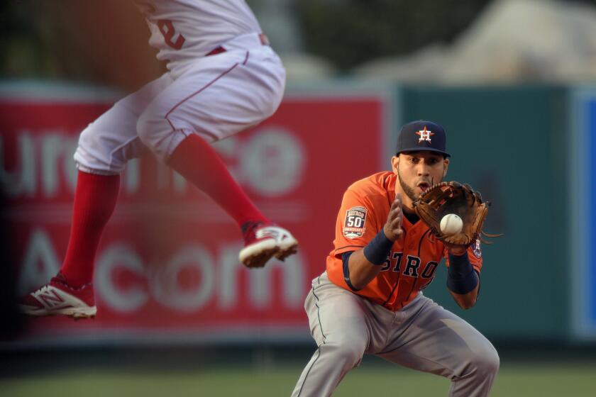 Angels' Erick Aybar, left, jumps out of the way as Houston shortstop Marwin Gonzalez fields the ball Saturday in Anaheim.