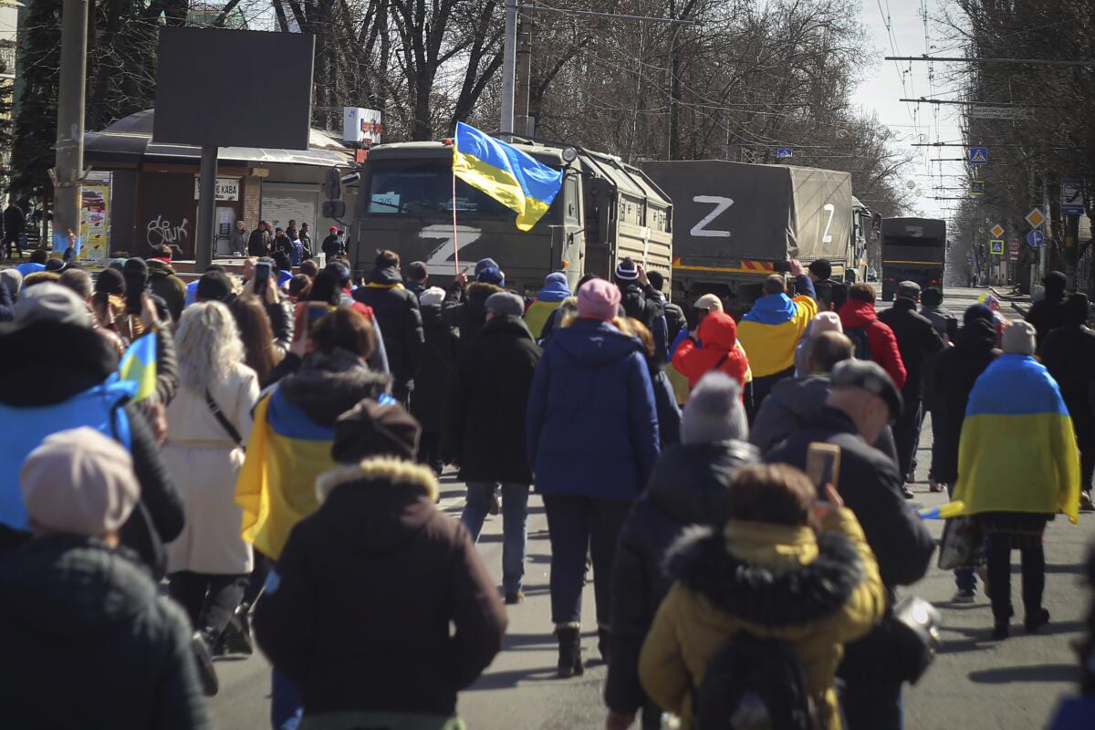 Personas con banderas ucranianas caminan hacia los camiones militares rusos durante una 