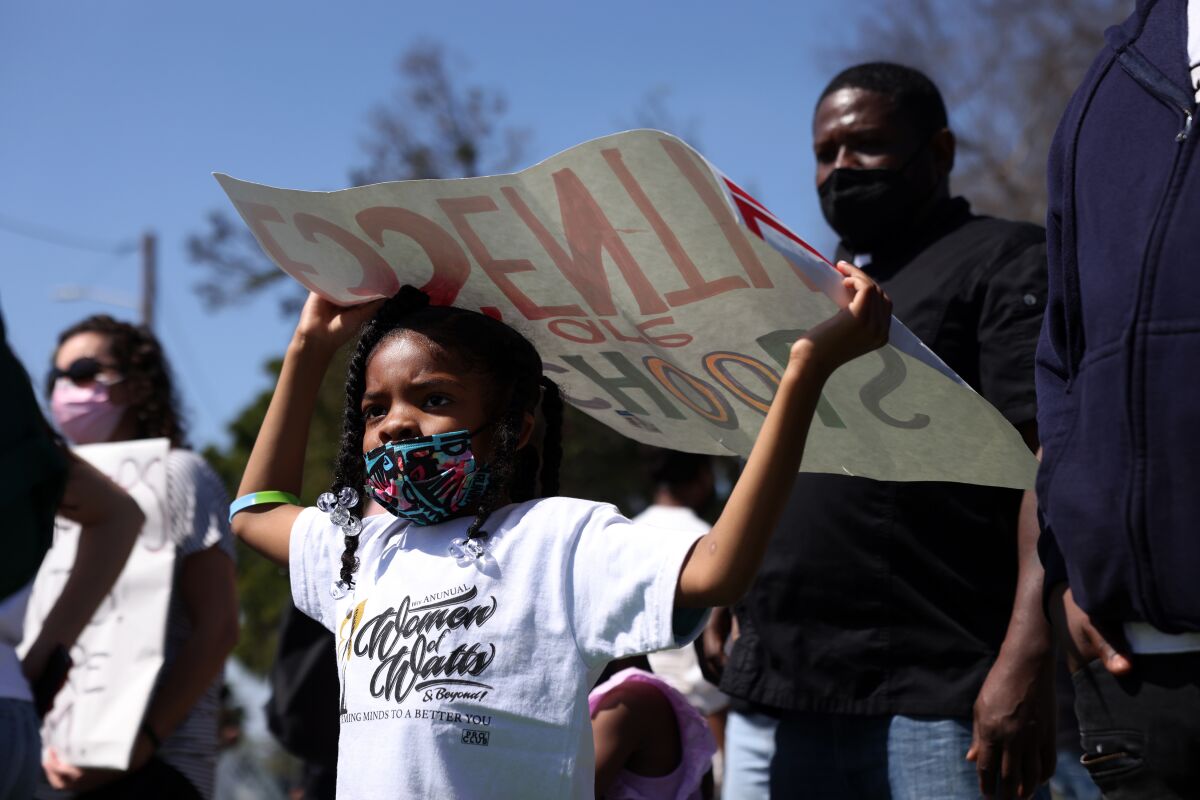 A student holds a protest sign up during a rally at Ted Watkins Park.