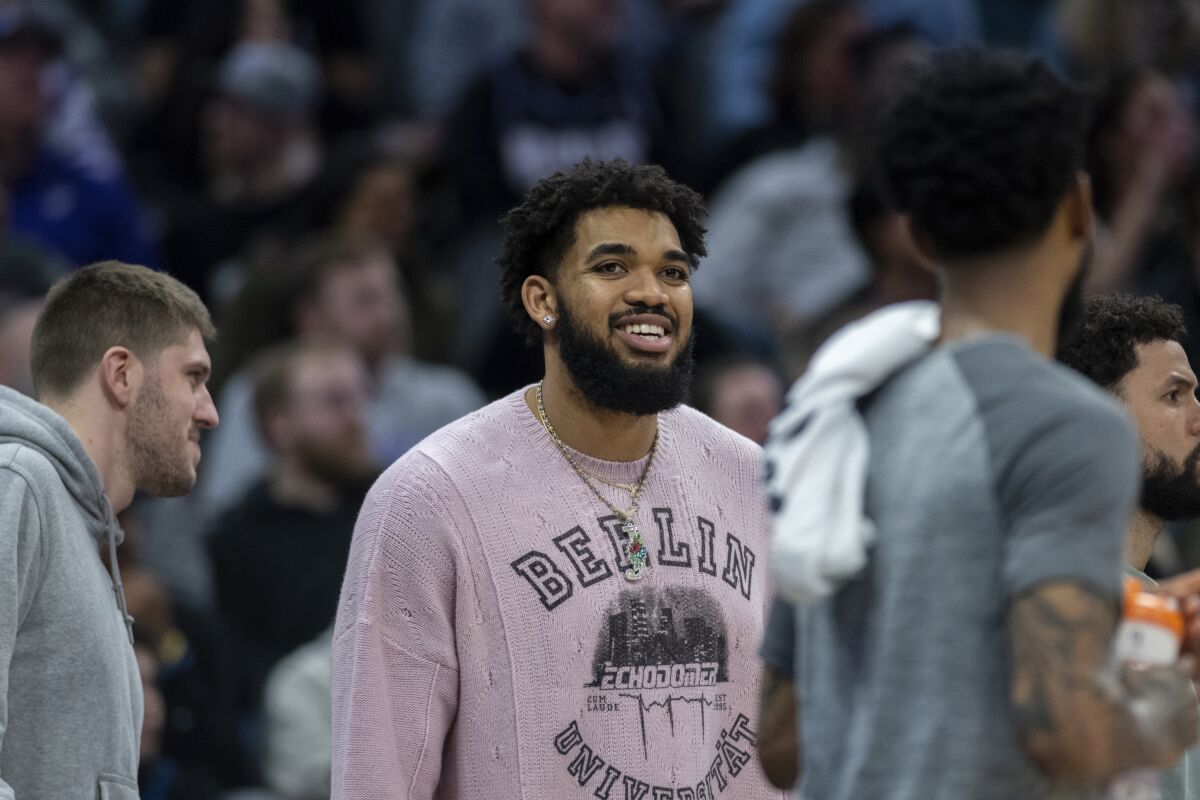 Minnesota Timberwolves center Karl-Anthony Towns, recovering from a knee injury, stands near the bench during the second half of the team's NBA basketball game against Sacramento Kings in Sacramento, Calif., Saturday, March 4, 2023. The Timberwolves won 138-134. (AP Photo/José Luis Villegas)