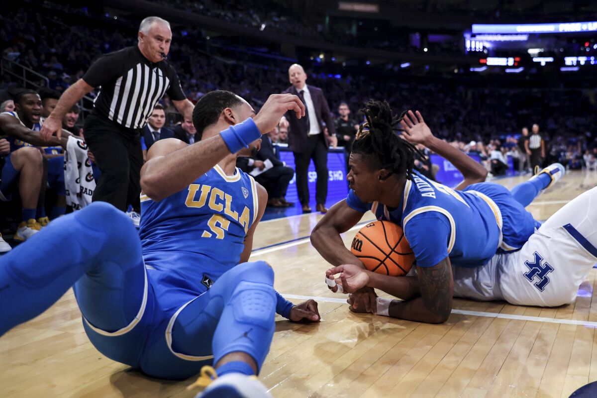 Kentucky guard Cason Wallace, UCLA guard Amari Bailey and forward Adem Bona fight for the ball on the floor.