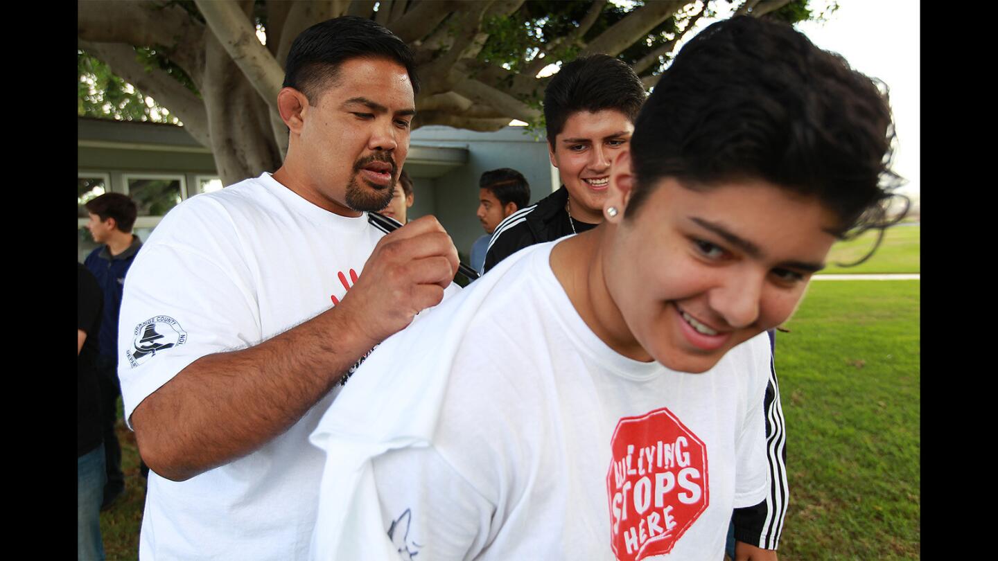 Mark Munoz, a former Ultimate Fighting Championship competitor, signs an autograph for Dylan Clark, 18, center, and Joey Hernandez, 17, at the Back Bay/Monte Vista High School campus on Tuesday in Costa Mesa.