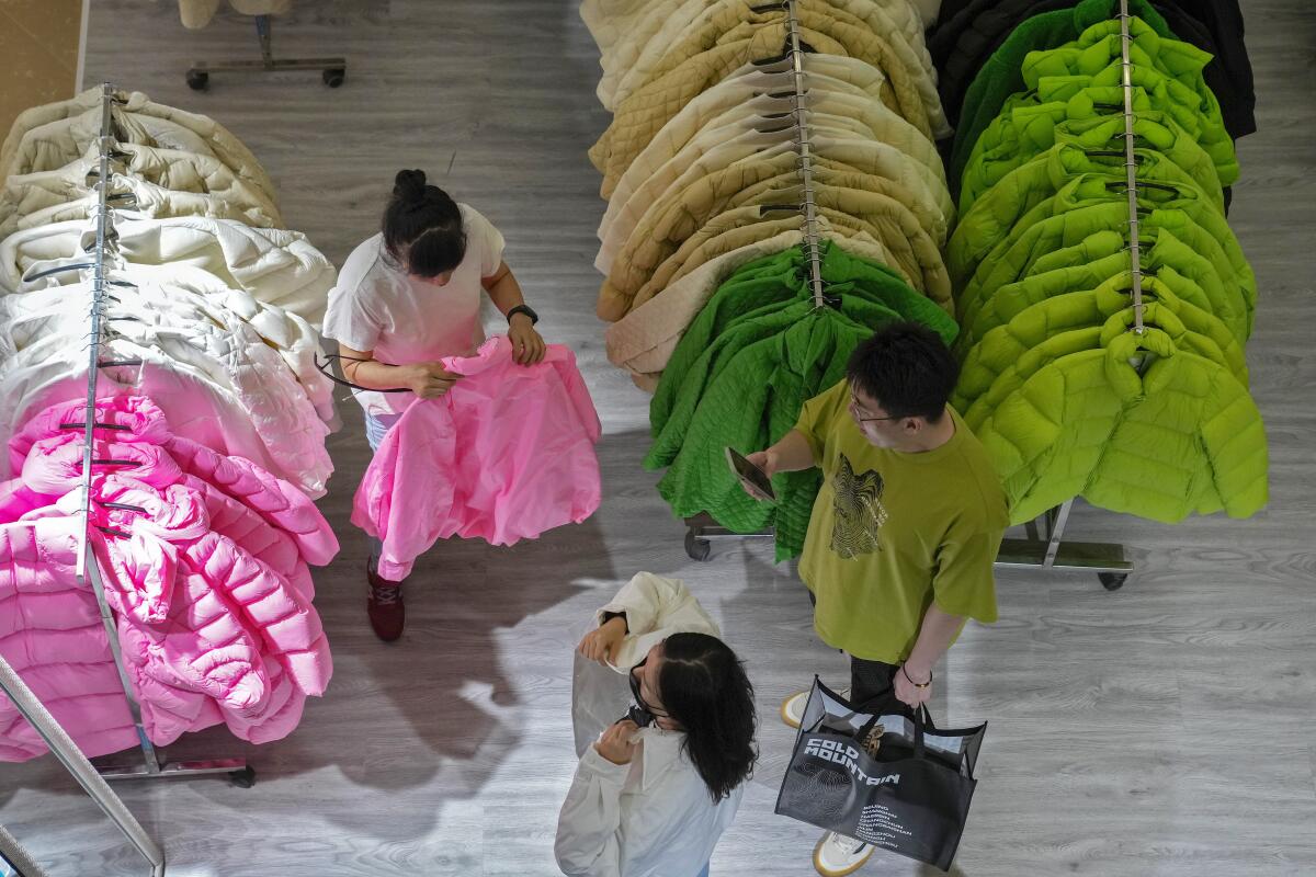 Женщина примеряет осенний наряд в киоске торгового центра в Пекине.
