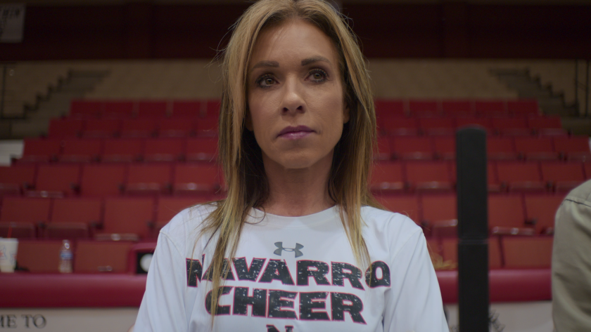 A woman in a Navarro College t-shirt stands with auditorium seats in the background