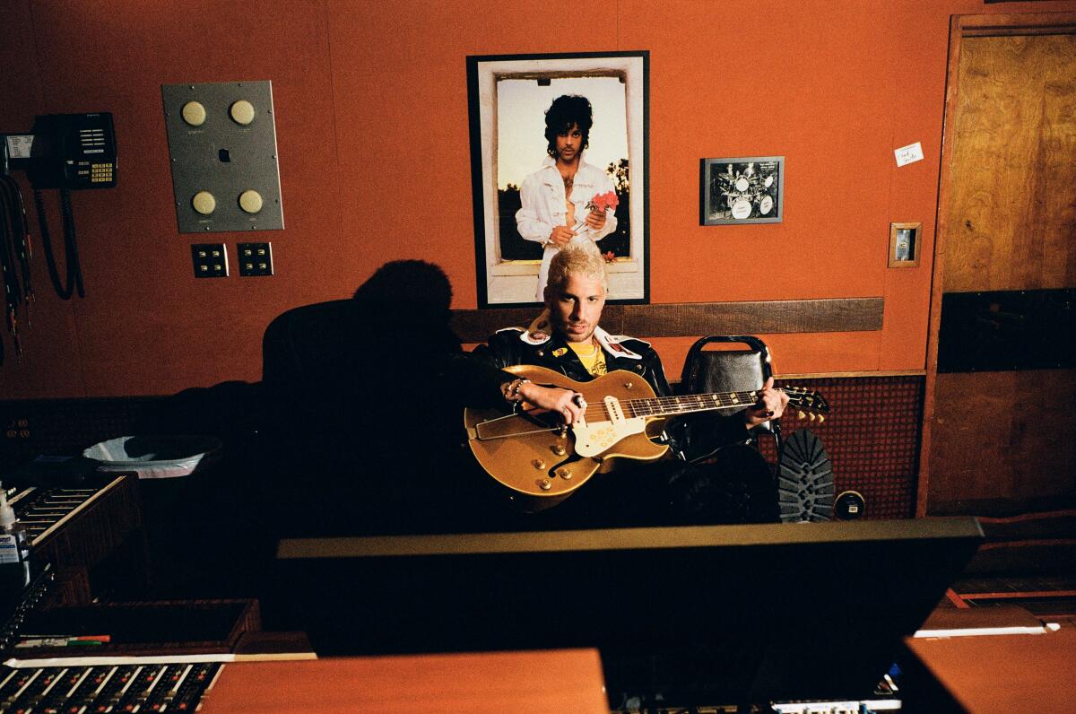 Man sitting in recording studio with guitar on top of photo of Prince