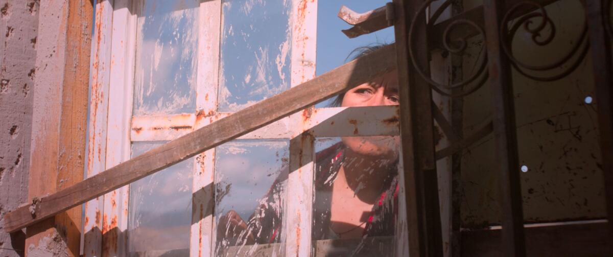 Mercedes Hernández peers out a window in the movie "Identifying Features."