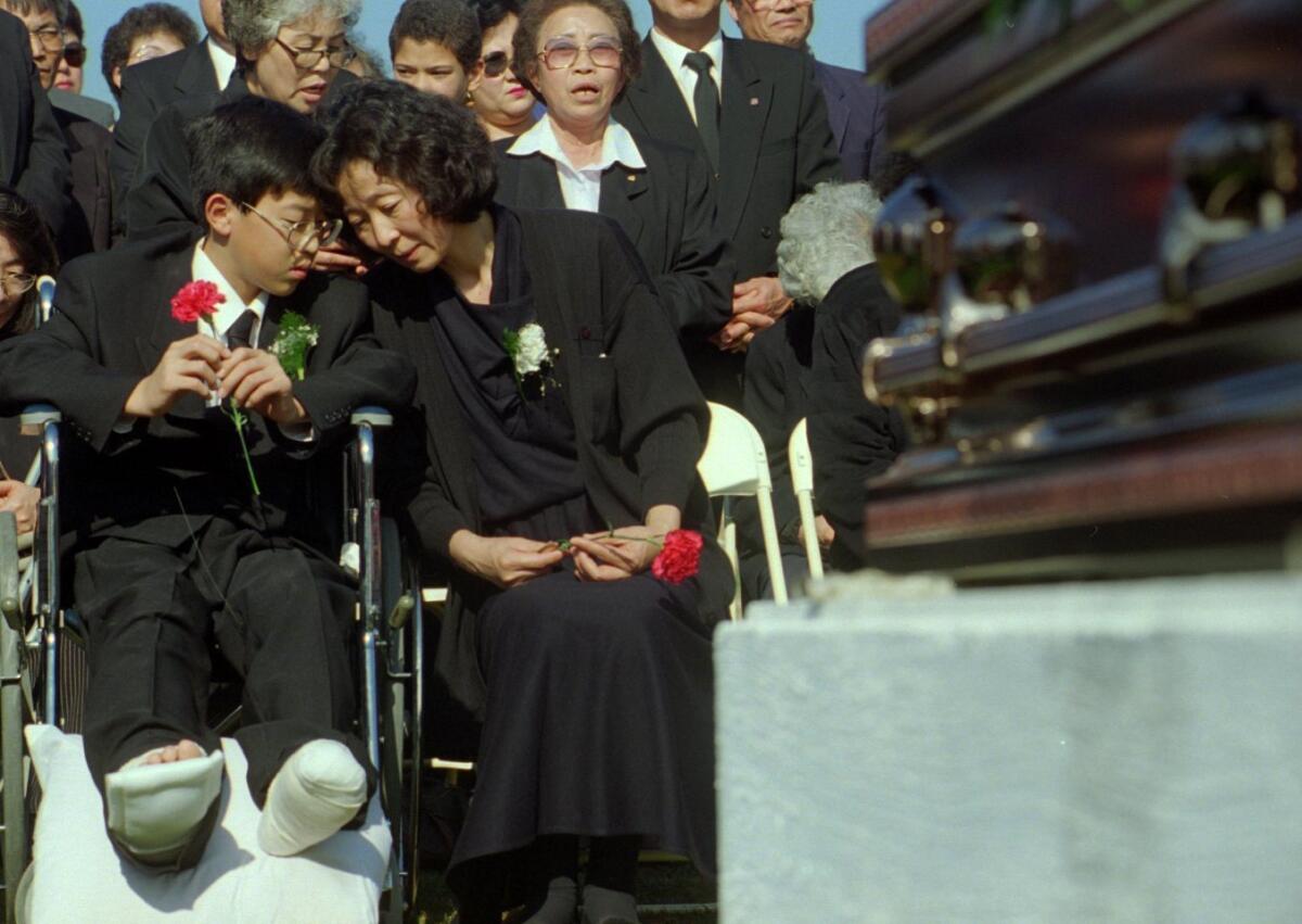 Mother Hyun Sook Lee and her son, Jason Lee, comfort each other at the graveside during a funeral for her husband, Pil Soon Lee, 47, and son Hawon Lee, 14, killed in the collapse of the Northridge Meadows apartment complex. Many of the 16 who died in the collapse suffocated from intense body compression from the weight of the destroyed building.