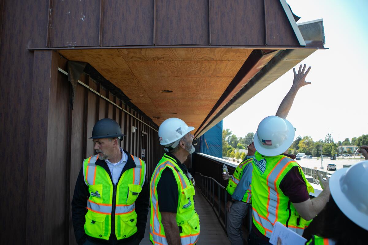 People in yellow vests and hard harts stand in a building under construction.