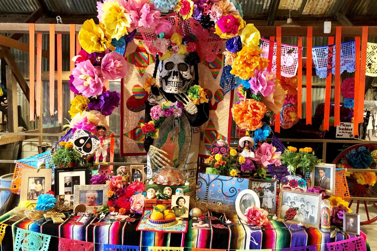 Día de los Muertos altar decorated with framed photos, food, paper flowers and mementos. 