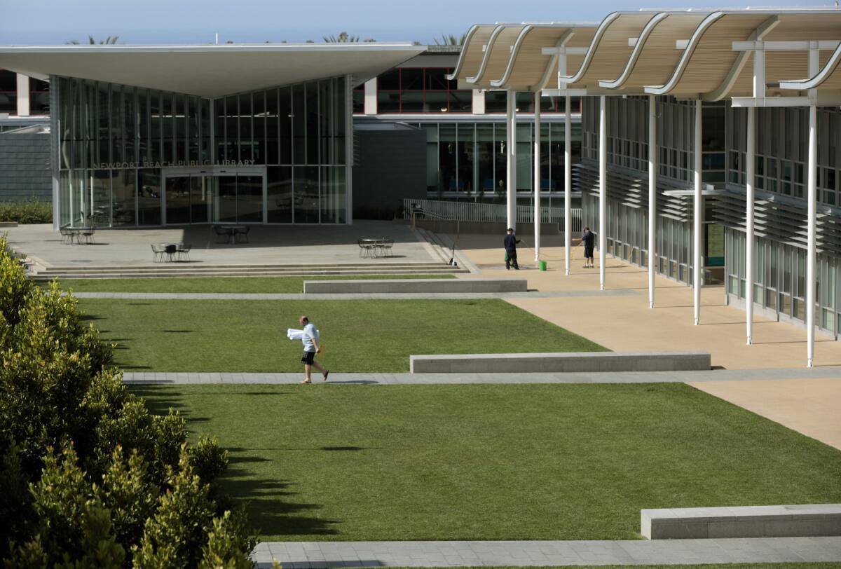 A pedestrian walks past the lawns between city hall and the public library in Newport Beach April 3, 2015. Newport Beach has been identified as one of the heaviest per-capita water-using cities in the state.