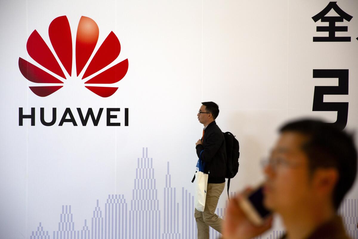 Men walk in front of a Huawei sign at a tech expo in Beijing in 2019 