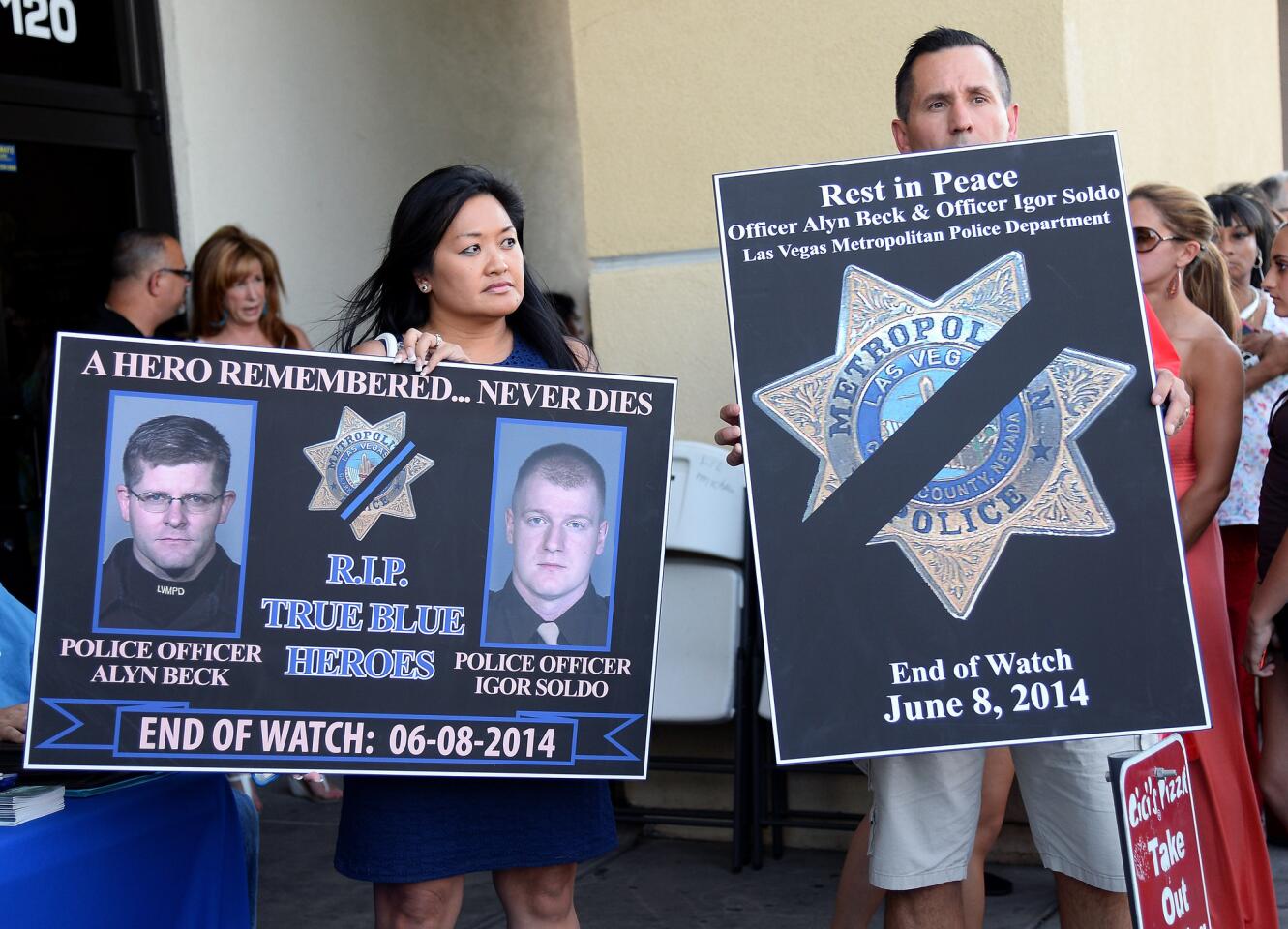 Minddie Lloyd, left, executive director of the Injured Police Officers Fund, and Las Vegas police Det. Richard Golgart hold signs during a vigil Monday for the two Las Vegas police officers and a bystander who were killed on Sunday.