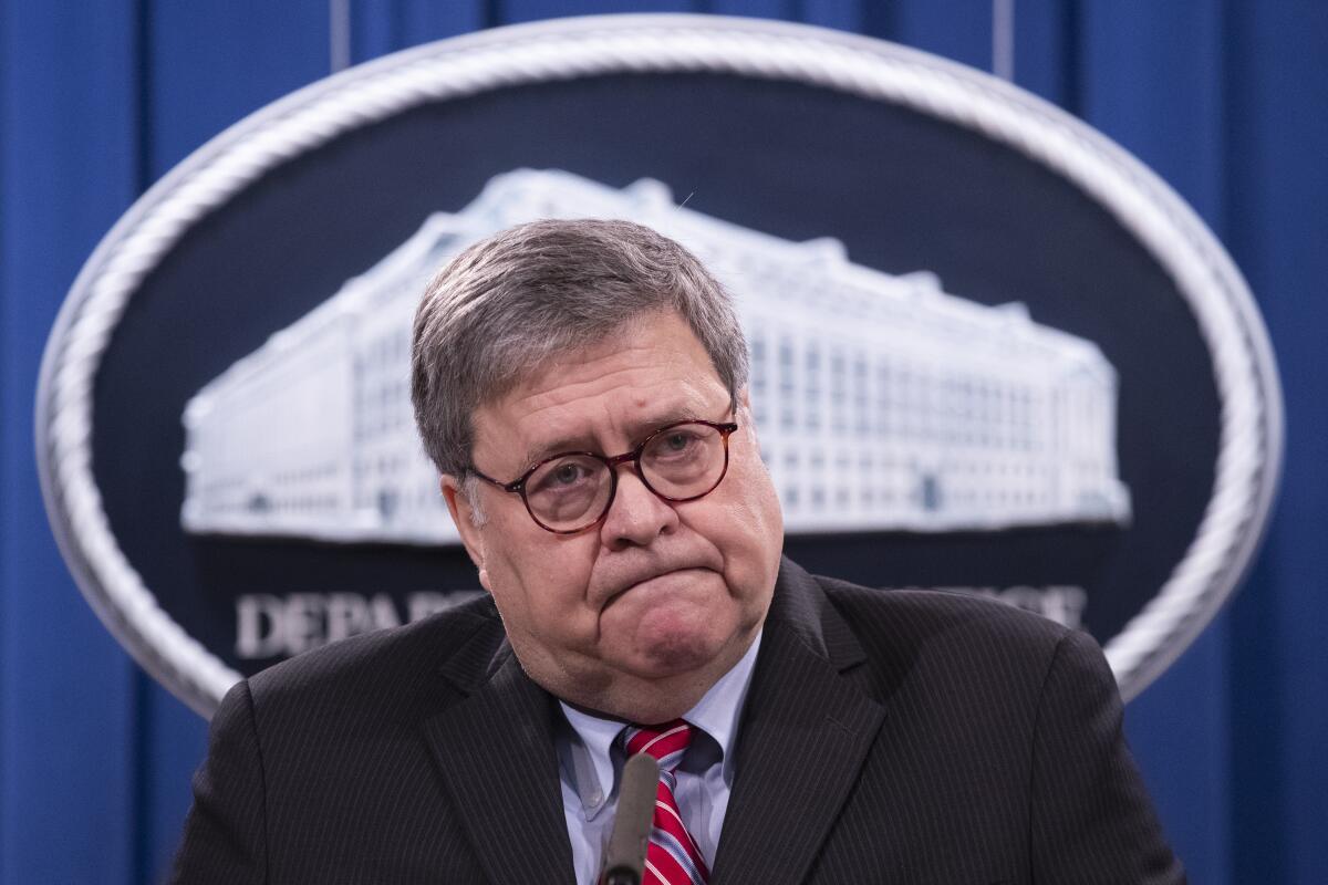 William Barr stands in front of the Department of Justice seal.