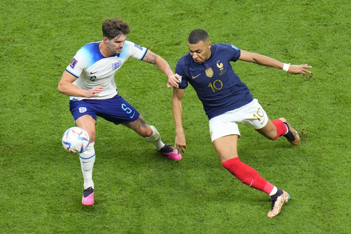 England's John Stones, left, challenges for the ball with France's Kylian Mbappe.