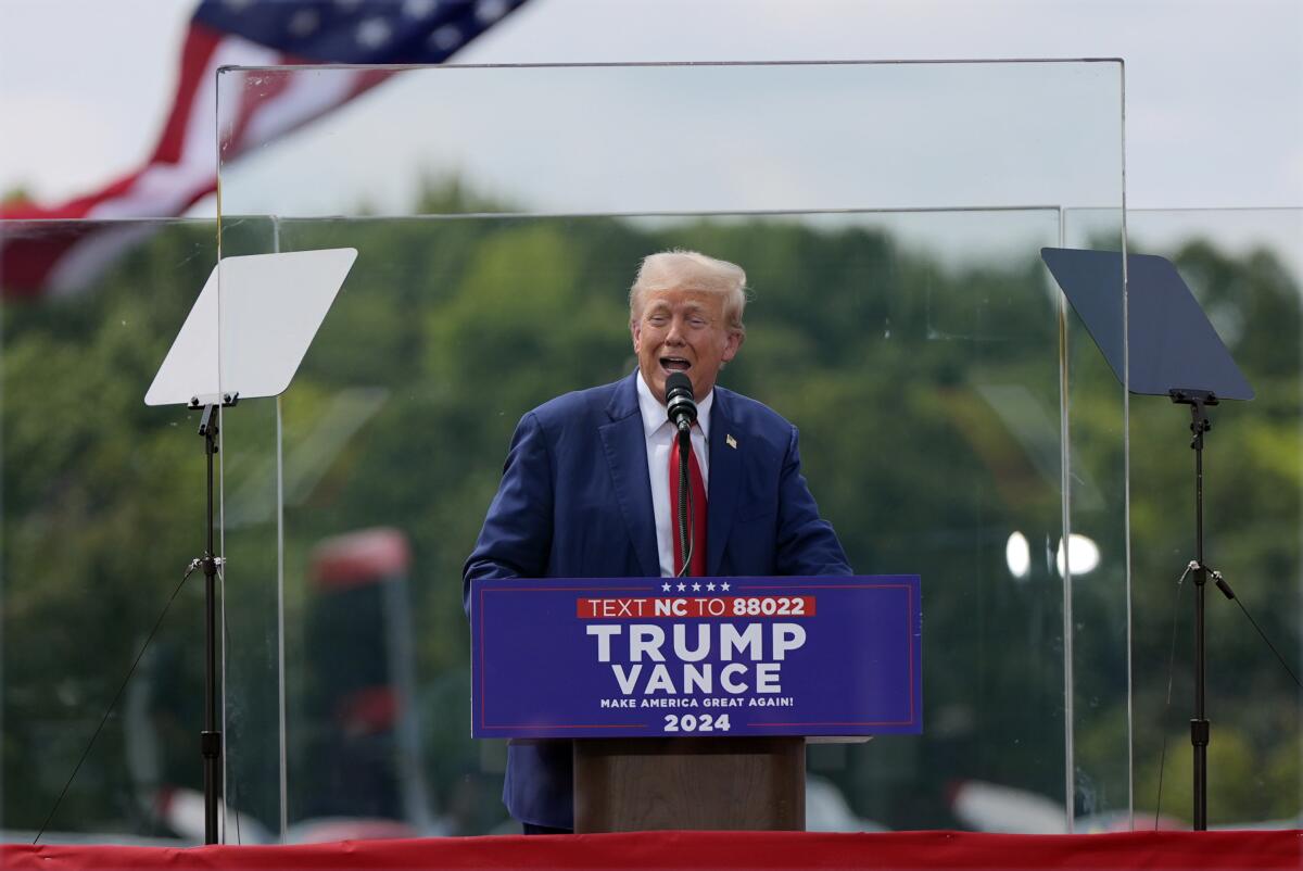 Former President Trump speaks outdoors from behind bulletproof glass