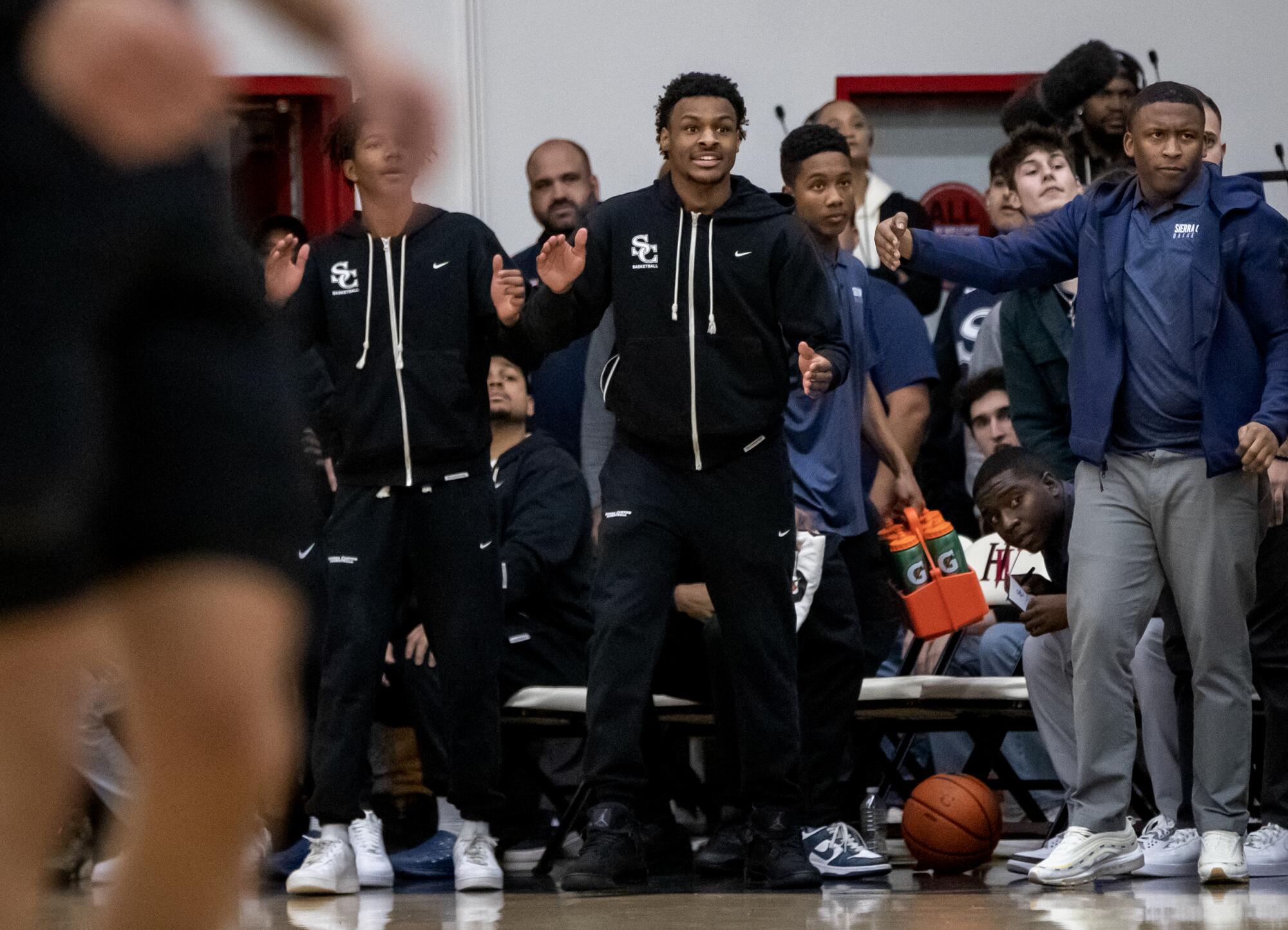 An injured Bronny James cheers from the bench during a game against Harvard-Westlake.