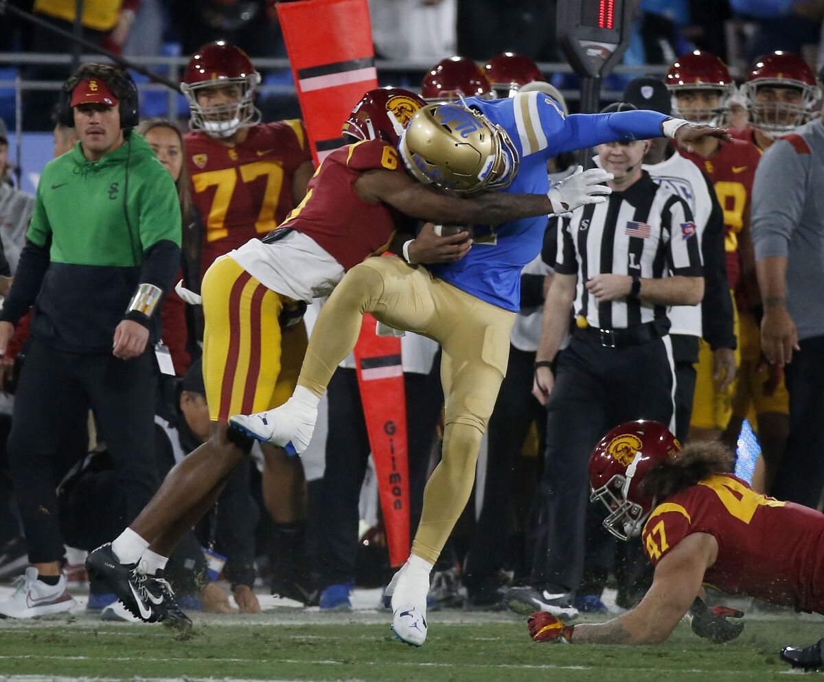 O cornerback da USC, Mekhi Blackmon, dá um grande golpe no quarterback da UCLA, Dorian Thompson-Robinson.
