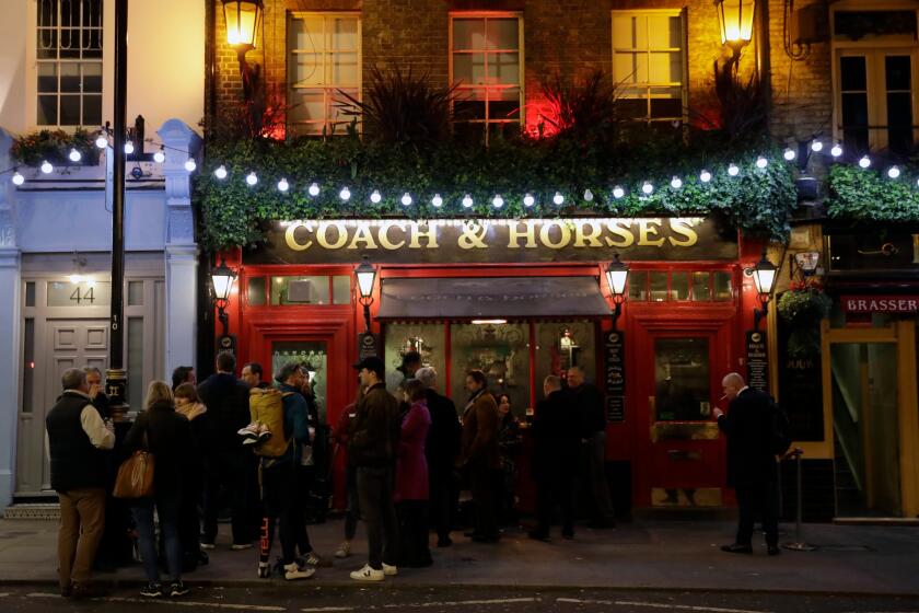 FILE - People stand drinking outside the Coach & Horses pub on Saint Patrick's Day in the Covent Garden district of central London, which is a popular tourist area, Tuesday, March 17, 2020. (AP Photo/Matt Dunham, file)