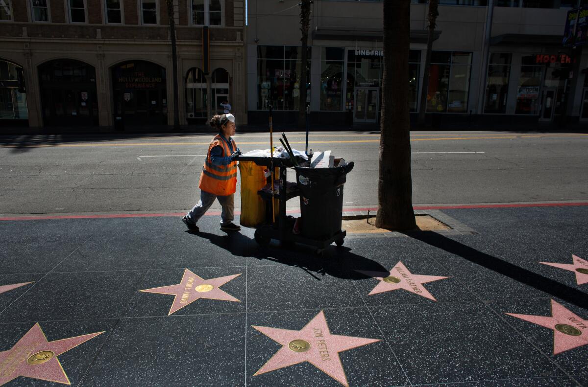 A city worker cleans nearly empty Hollywood streets on Thursday, March 26, 2020.