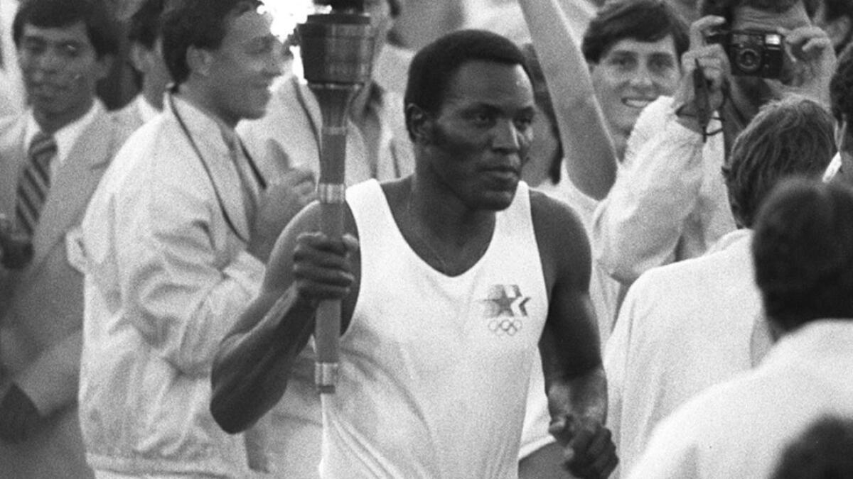 Rafer Johnson runs around the track at the Coliseum before lighting the Olympic flame in 1984.