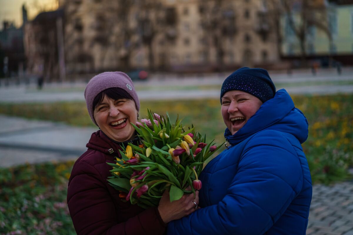 Two smiling women hold tulips.