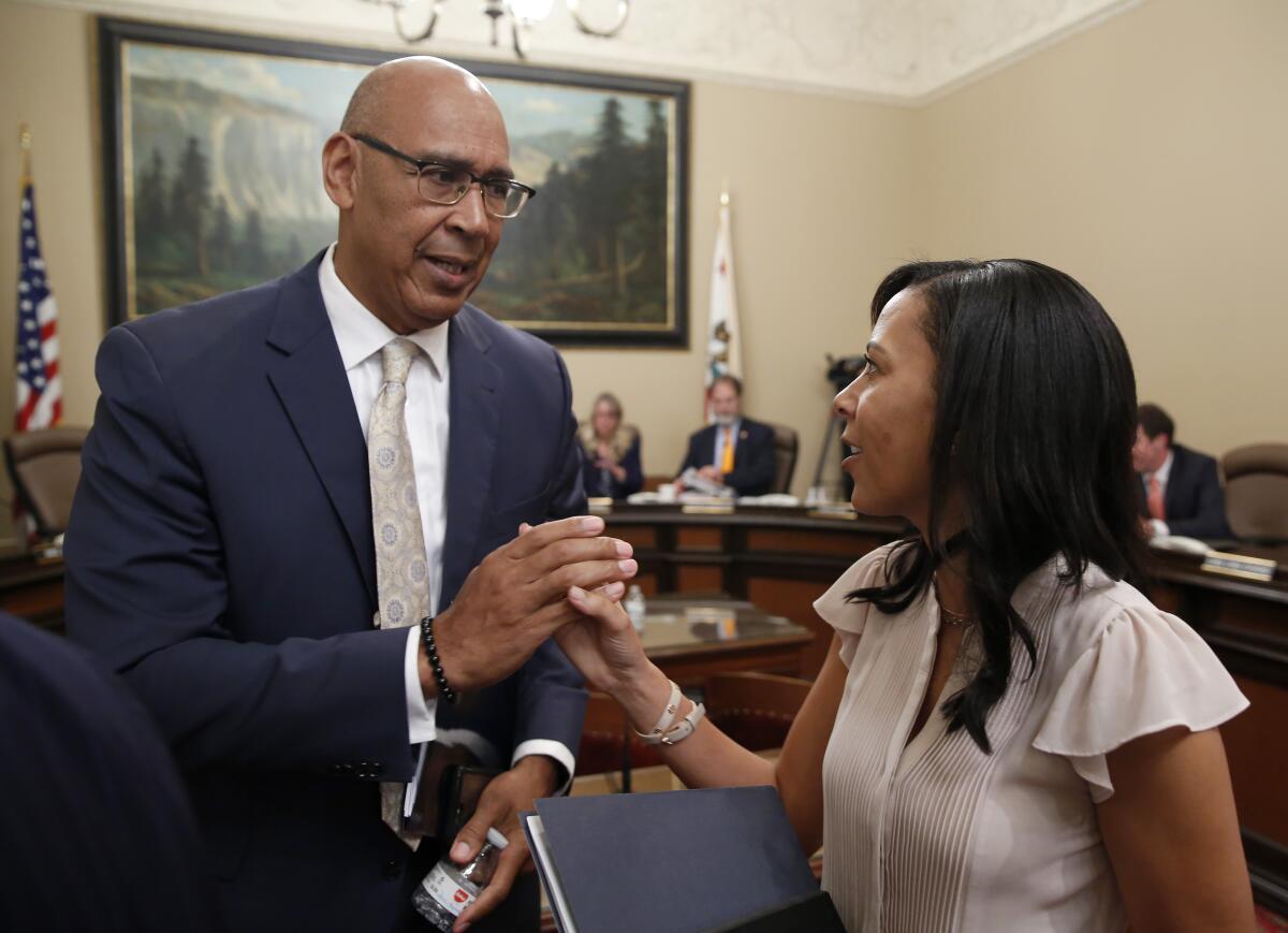 California Assemblymember Chris Holden, left, shakes hands with Assemblymember Autumn Burke in July 2019.