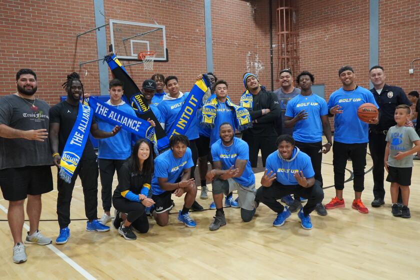 Members of the Bruin Fan Alliance pose on a basketball court.