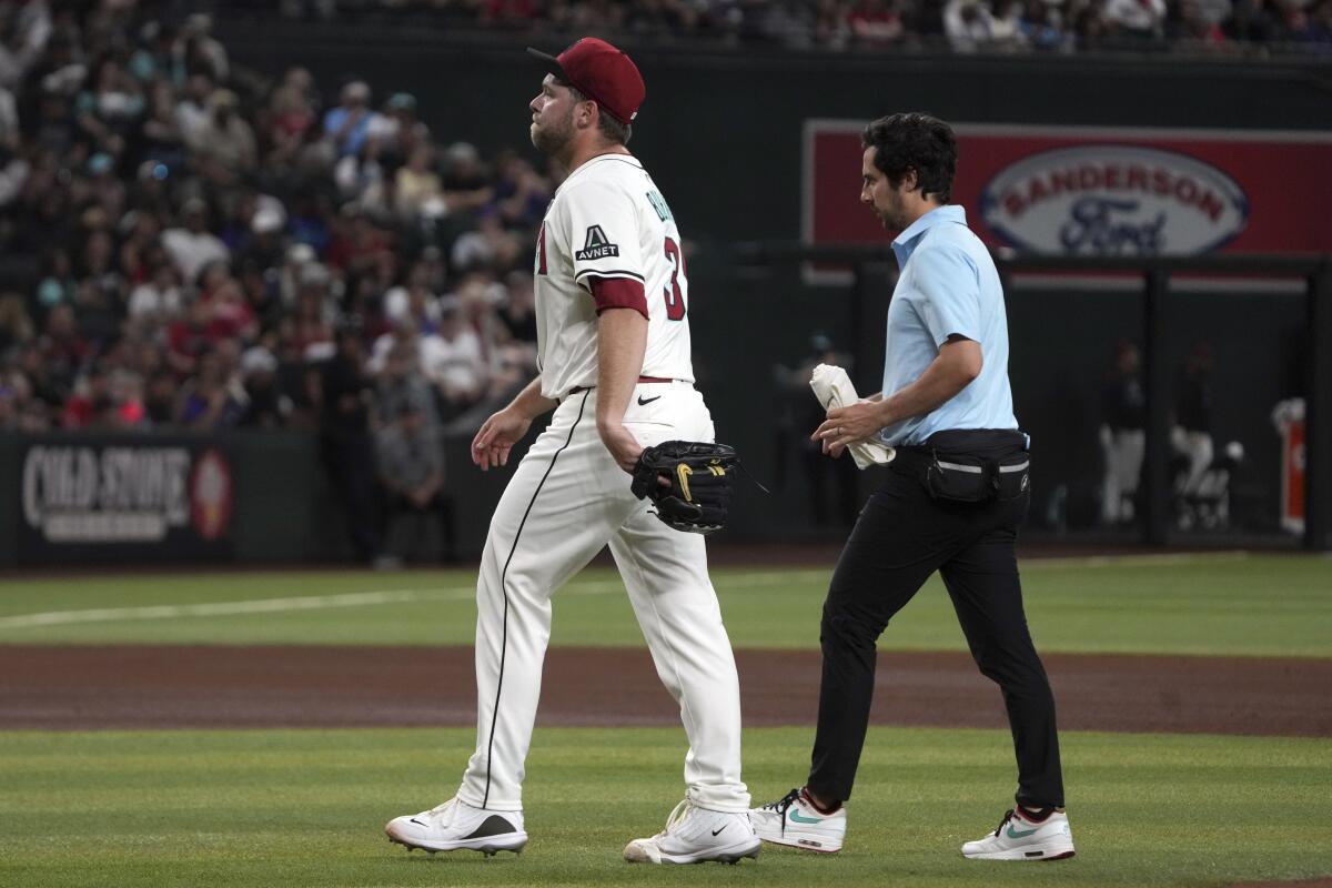 Arizona Diamondbacks pitcher Corbin Burnes, left, walks off the field with a team trainer.