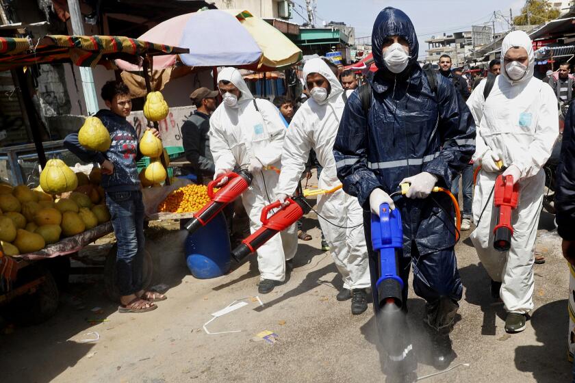 Workers wearing protective gear spray disinfectant as a precaution against the coronavirus, at the main market in Gaza City, Thursday, March 19, 2020. The Middle East has some 20,000 cases of the virus, with most cases in Iran or linked to travel from Iran. The vast majority of people recover from COVID-19. (AP Photo/Adel Hana)