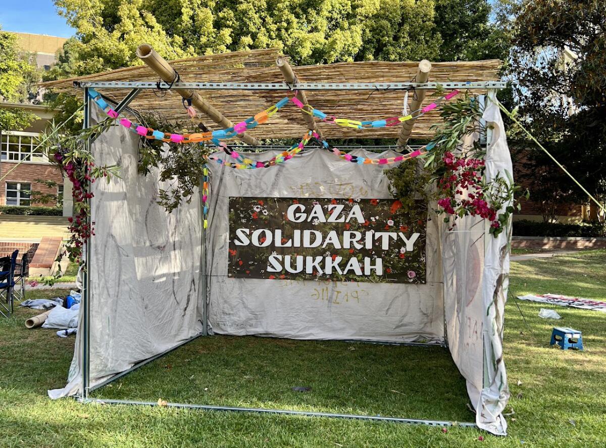 A three-sided tent with bamboo covering and a sign that says "Gaza solidarity Sukkah."