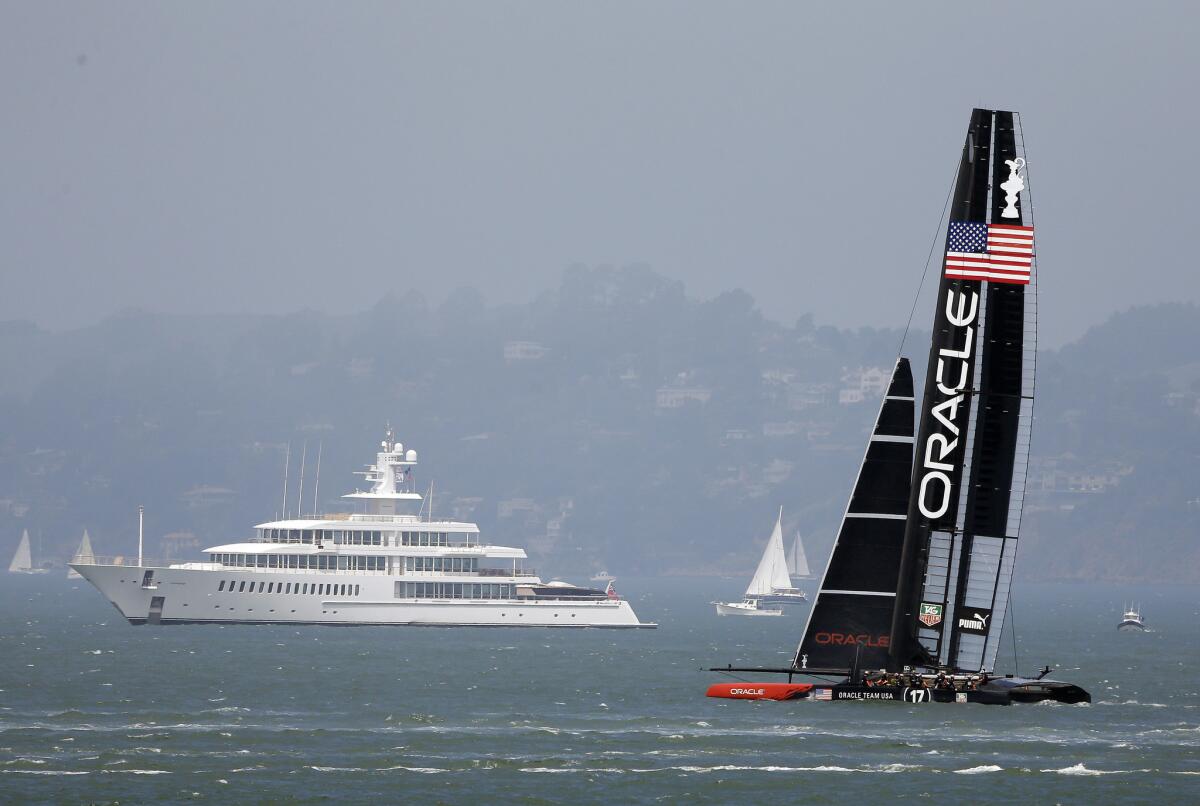 Larry Ellison's Oracle Team USA catamaran trains for the America's Cup sailing event in San Francisco Bay. In the background is Ellison's yacht.